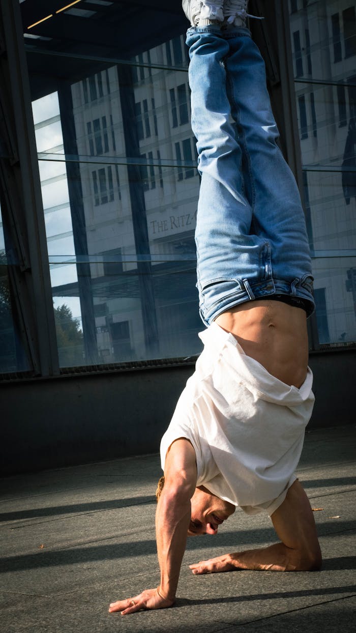 A man performing a handstand in urban city streets, showcasing strength and balance.